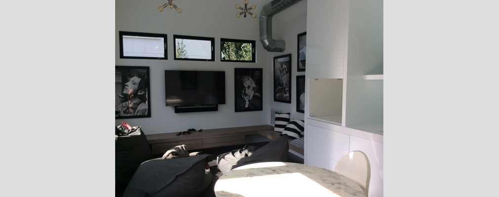 An interior view of an accessory unit showing a sitting area with a television and framed pictures on one wall.