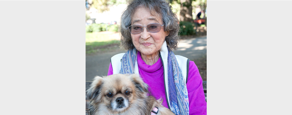 An older woman poses for the camera holding her dog.