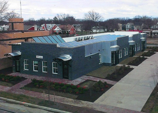 A photograph taken approximately 30-feet above street level showing the front and side façades and the solar panels on the roof of the seven unit senior building, a brick, one-story structure (courtesy of Better Housing Coalition). 