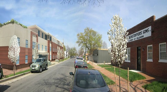 An enhanced photograph taken at street level depicting the rehabilitated Beckstoffer’s Mill building (a 1-story brick building) in the foreground on the right side of a street and renderings of two soon-to-be-completed senior apartment buildings in the background on the right side of the street (a 1-story brick building) and on the left side of the street (a 3-story brick and panel building) (courtesy of Better Housing Coalition). 