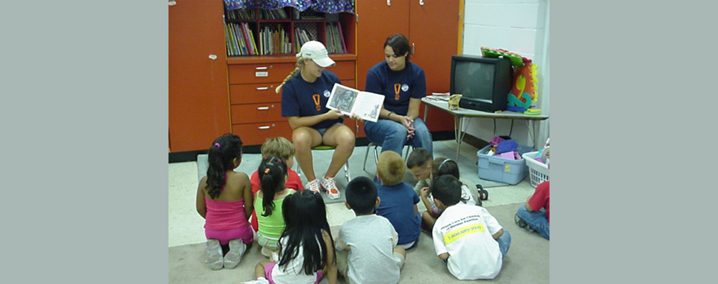 Photograph of two IUPUI students reading to young children.