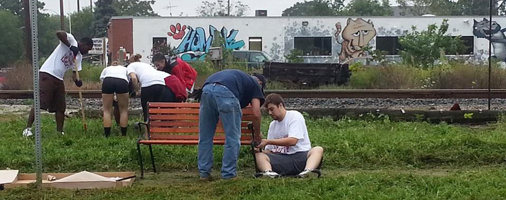 Photograph of IUPUI student volunteers cleaning a neighborhood park and installing a park bench.