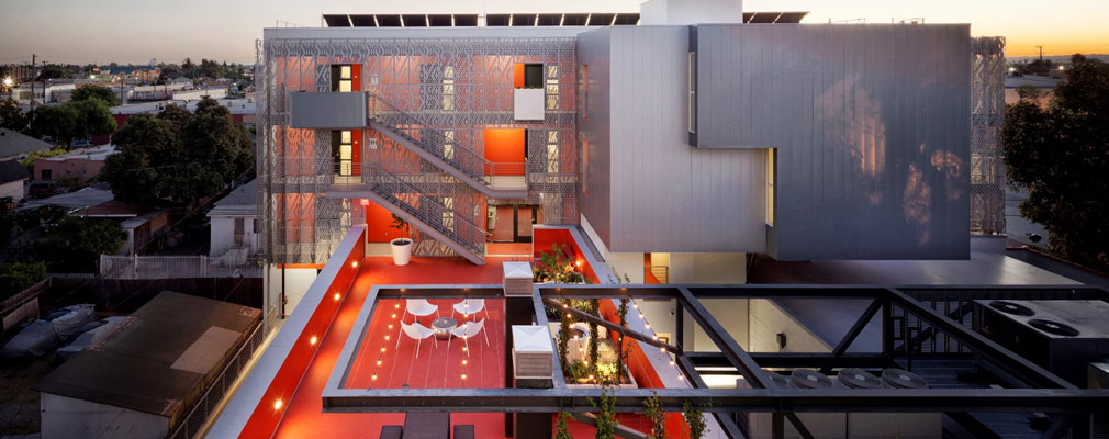 Photograph showing a rooftop garden and the north façade of the new building. Also pictured is a metal trellis holding mechanical equipment.