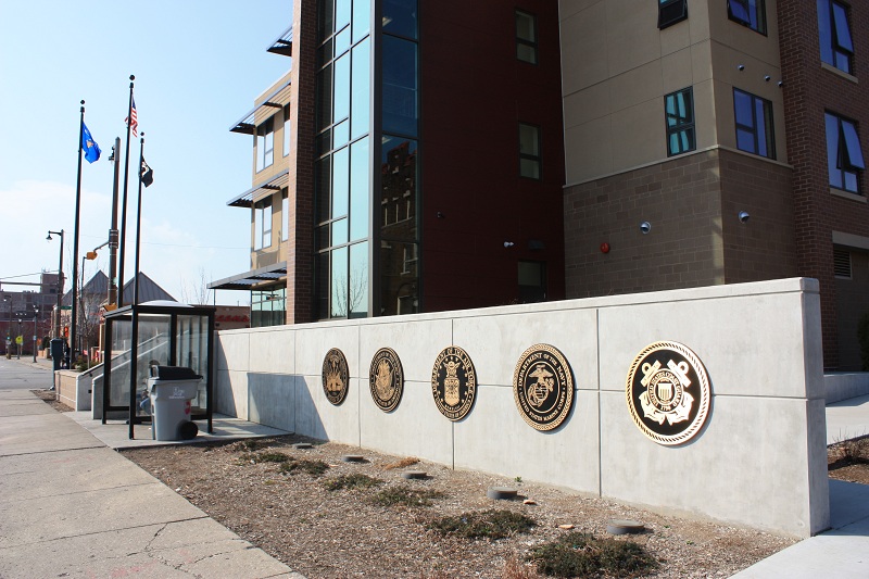 The U.S., Wisconsin, and Prisoner of War flags and medallions of the five branches of the military mark the entrance to Veterans Manor.