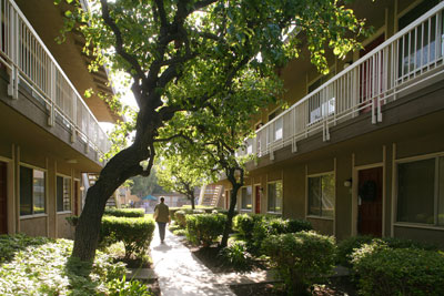 Person walking in landscaped area between two buildings of City Gardens Apartments.