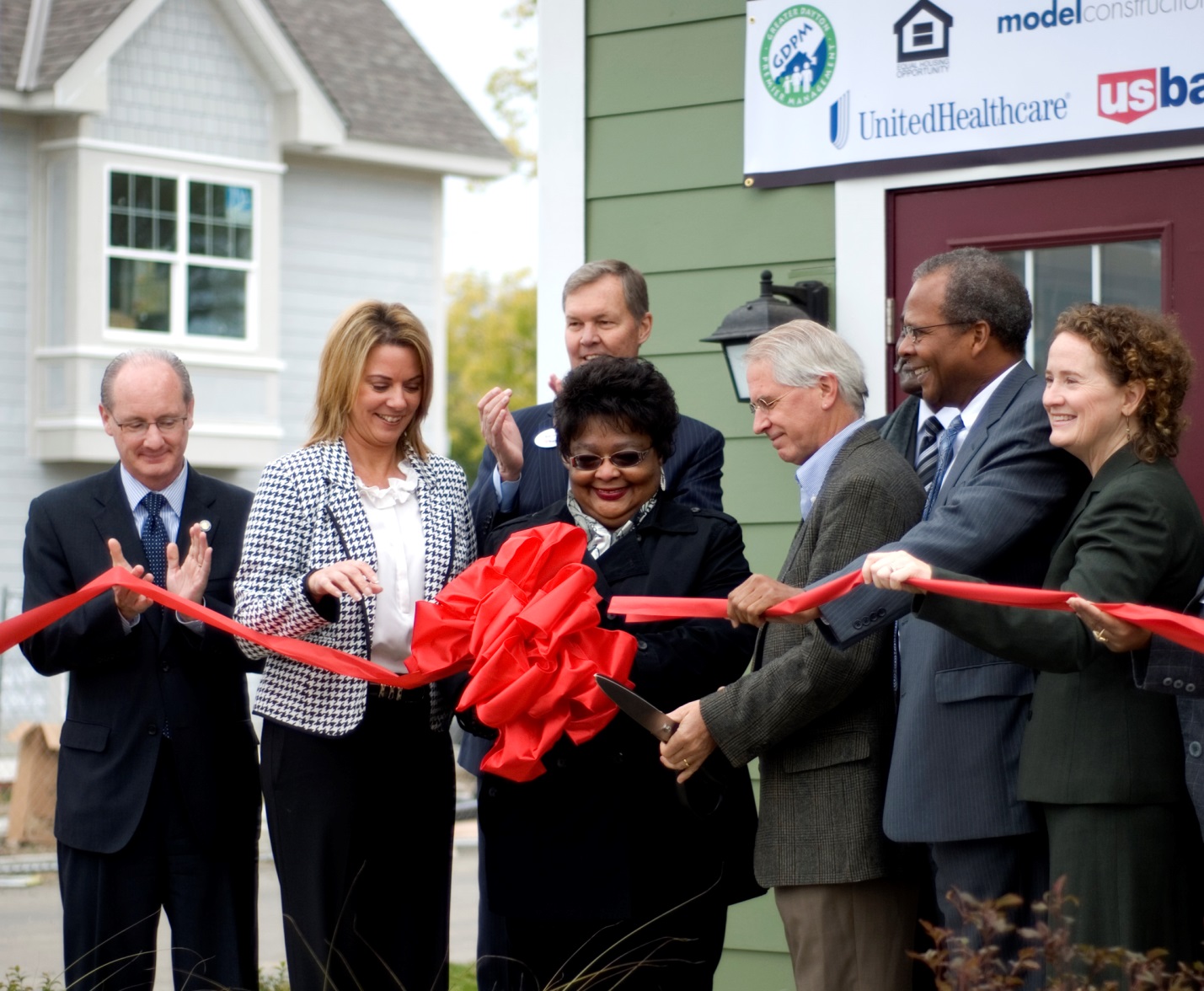 Photograph of eight people cutting a ribbon to officially open the Germantown Village development.