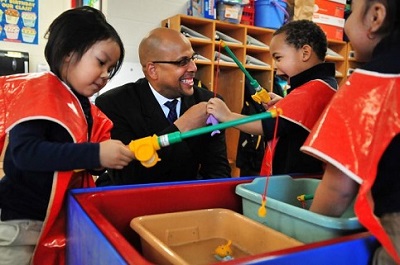 Assistant Deputy Secretary Jim Shelton shown with a group of children after announcing the $28 million Promise Neighborhoods grant for the Northside Achievement Zone at Elizabeth Hall International Elementary School in Minneapolis on Dec. 19.