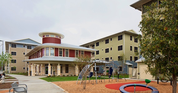Sustainable multifamily housing with outdoor playground and child learning center in foreground.
