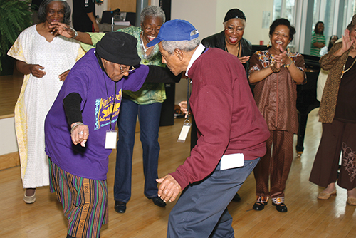 An elderly dancing couple, surrounded by fellow East Point NORC members who are applauding and enjoying their “moves.”