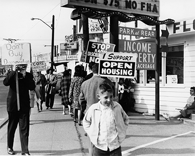 Protesters holding signs march at a demonstration in 1964 in Seattle, Washington.  