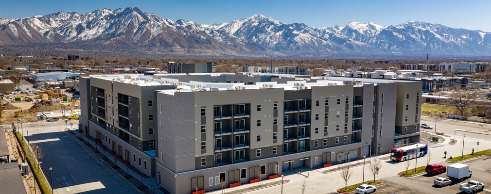 Low-angle aerial photograph of a five-story building, with mountains in the background.