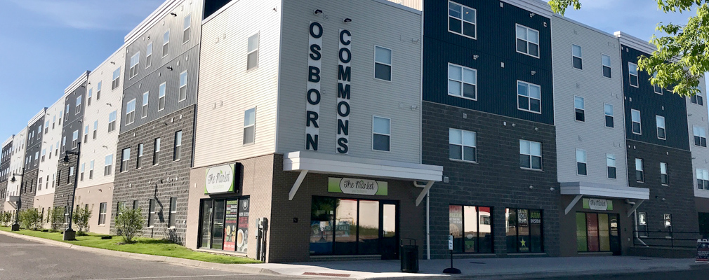 Two street façades of a four-story building with “Osborn Commons” written vertically above a first-floor retail space.