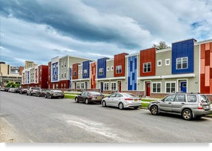 Photograph of the front façade of two-story townhouses and a three-story multifamily building.