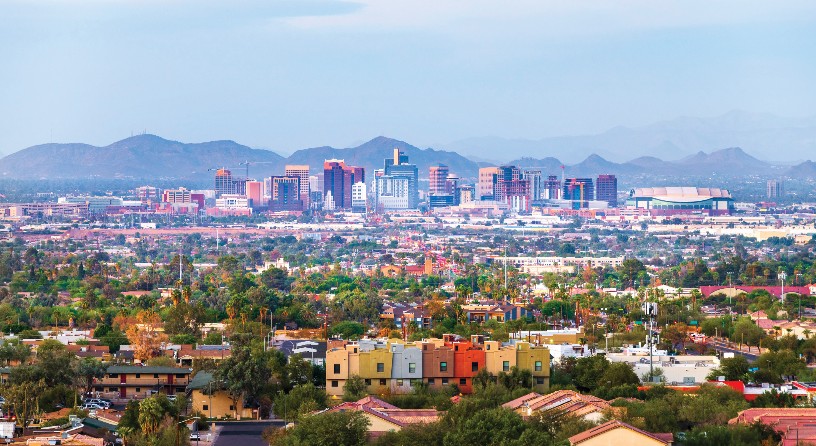 A low-angle aerial view of city of Phoenix with the downtown and mountains in the background.
