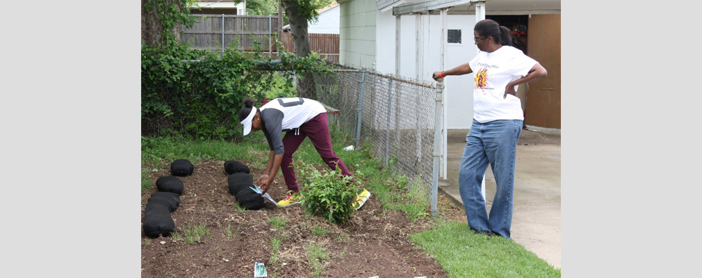 Photograph of two volunteers working in a backyard vegetable garden.