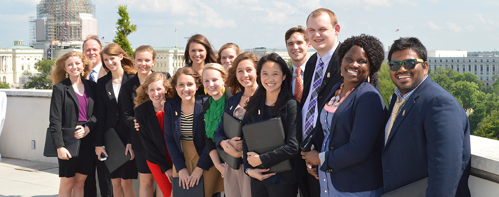 Photograph of 15 students and faculty with the capitol in the background.