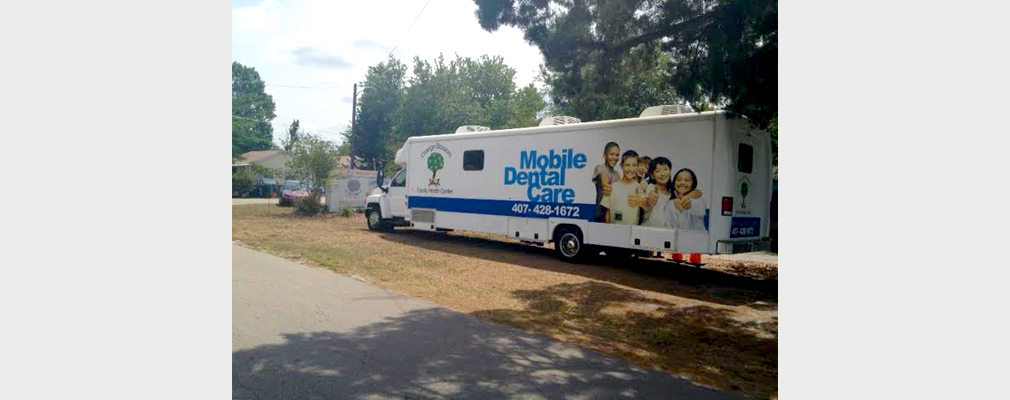 Photograph of the side of a mobile dental office with a sign reading, “Mobile Dental Care.”