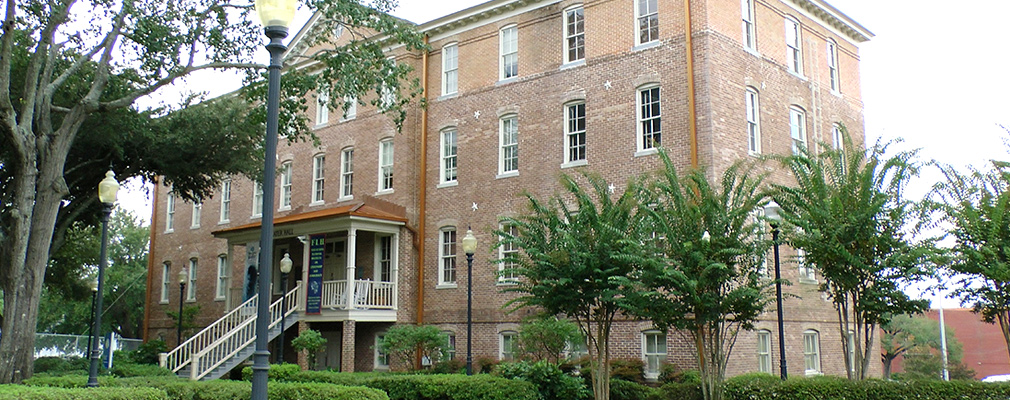 Photograph of a four-story brick institutional building, Ayer Hall, the university’s oldest building, dating from 1903.
