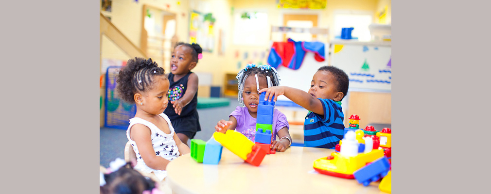Photograph of several children playing with stacking blocks in a classroom.