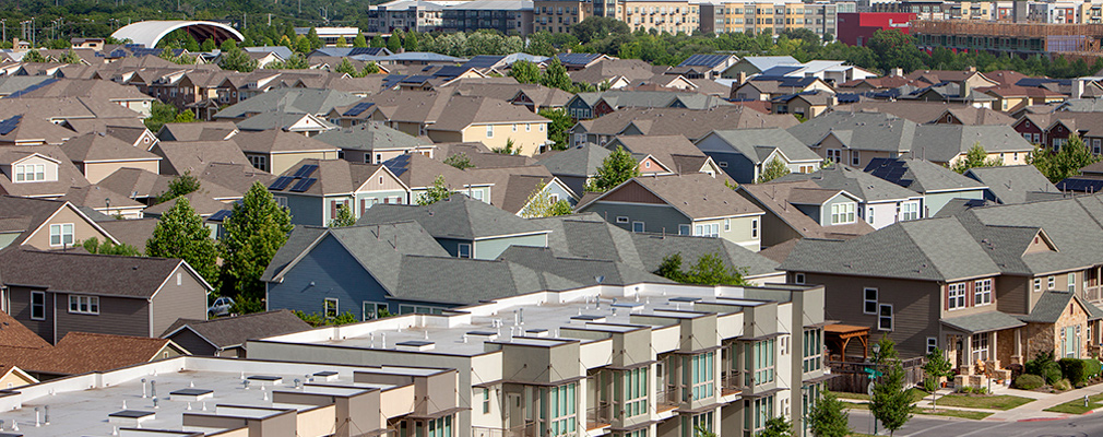 Photograph taken at roof height of townhouses and single-family detached houses, with multifamily housing in the background.