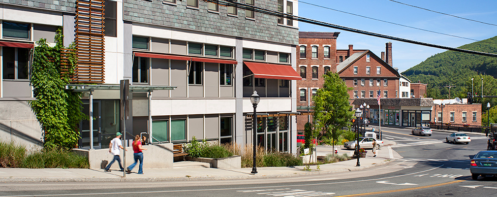 Photograph of a four-story mixed-use building with a sidewalk and street in the foreground.