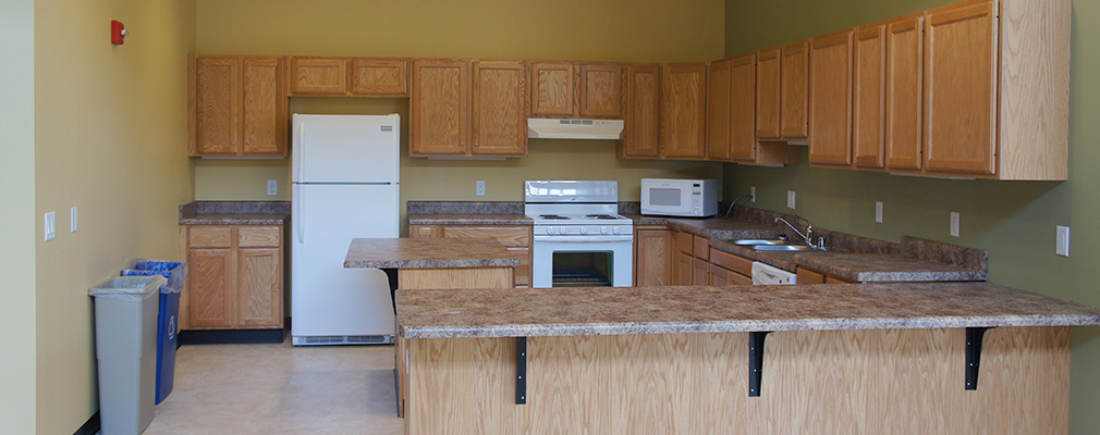 Photograph of a large kitchen with a refrigerator, oven, and microwave.