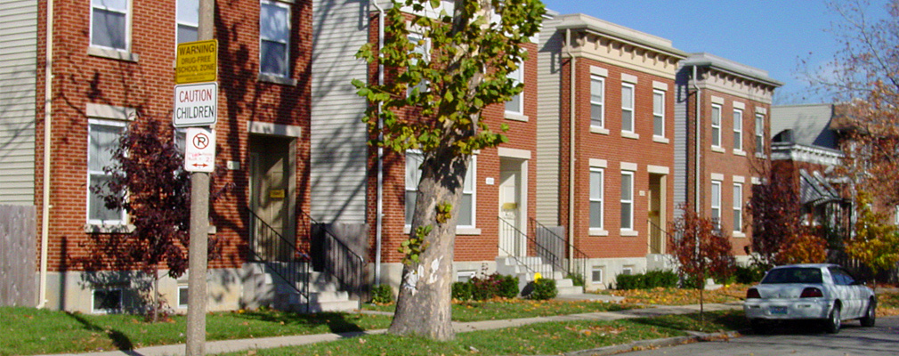 Photograph of four two-story, single-family dwellings with brick façades. 