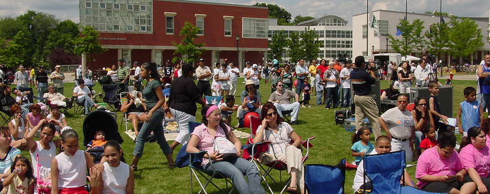 Photograph of a large crowd sitting on the lawn of the Learning Corridor during a community.