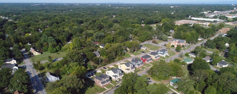 Low-angle aerial photograph of seven newly constructed two-story houses in a low-density neighborhood. 