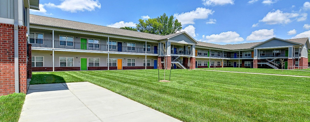 Photograph of a two-story apartment building surrounding a grass courtyard.