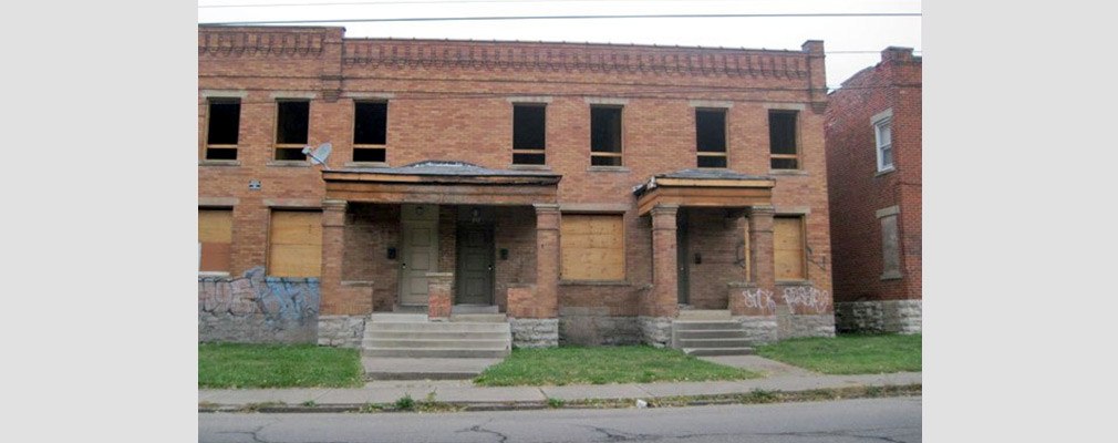 Photograph of the front façades of three vacant, two-story townhouses.