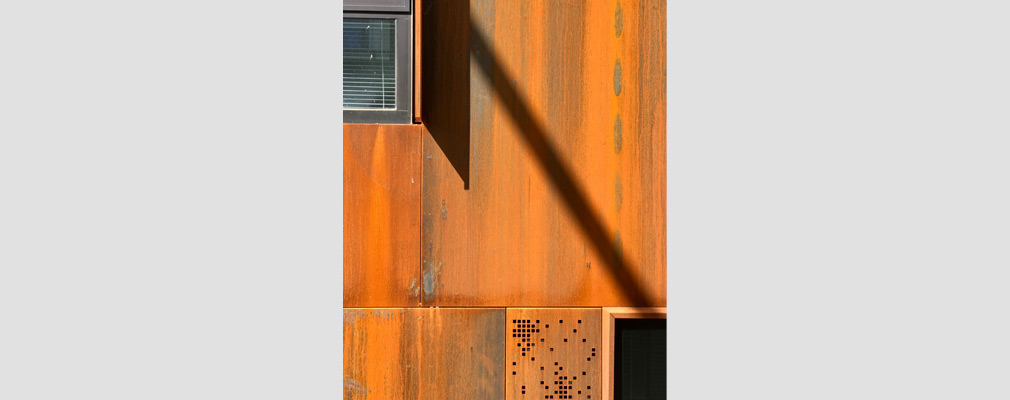 Photograph of weathered steel panels on a façade of the apartment building.
