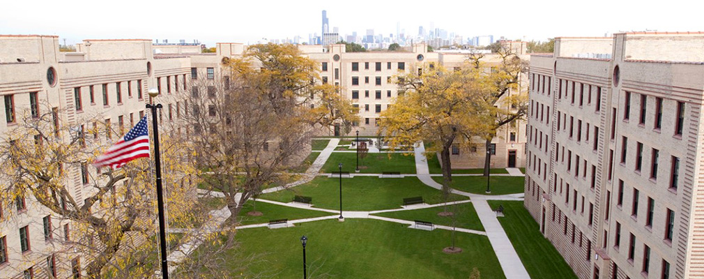 Photograph of the interior courtyard framed by the five-story multifamily building with the downtown Chicago skyline in the background.