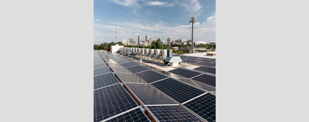 Photograph of rooftop photovoltaic panels, with the skyline of downtown New Orleans in the background.