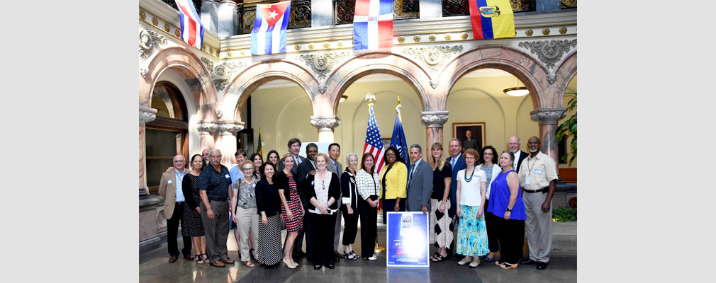 Photograph of 25 community stakeholders and city officials standing in Rochester’s city hall behind a poster that says “Let’s Make Lead History.”