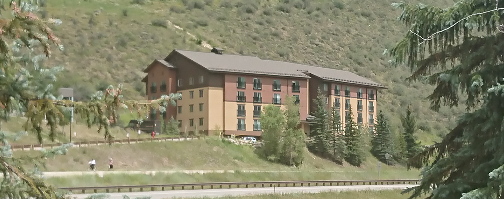 Photograph of a five-story apartment building standing at the foot of a mountain.