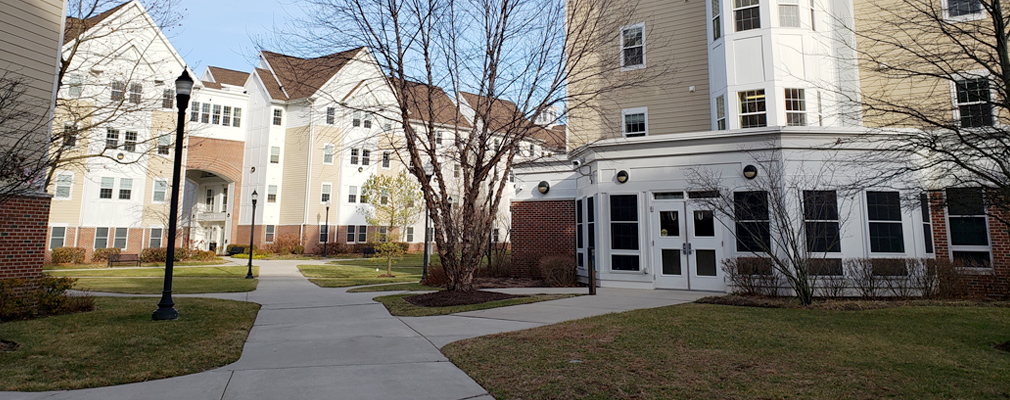 Photograph of four-story residential buildings framing a landscaped courtyard.