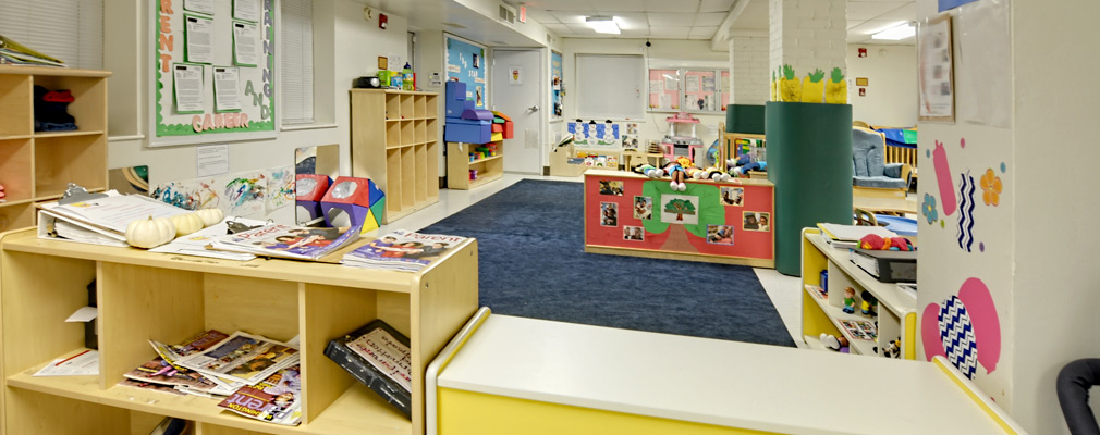 Photograph of a large classroom with storage cubes, books, and toys.