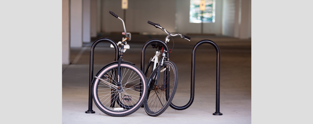 Photograph of a metal bicycle rack with two bicycles in a ground-level parking garage. 