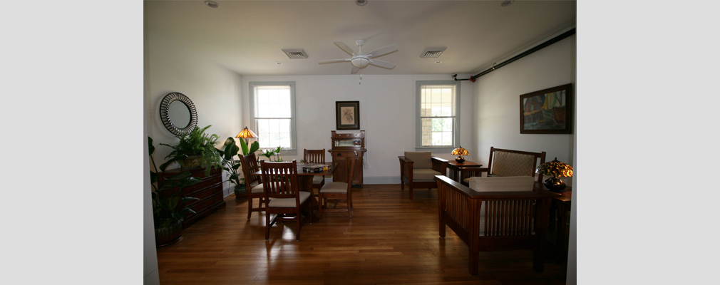 Photograph of a large room with several mission-style chairs and tables and potted plants.