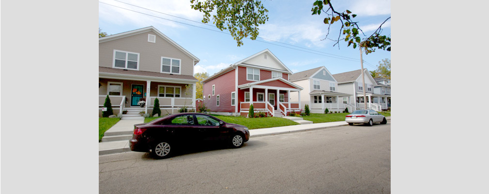 Photograph of the front façades of four two-story single-family houses, each with a front porch.