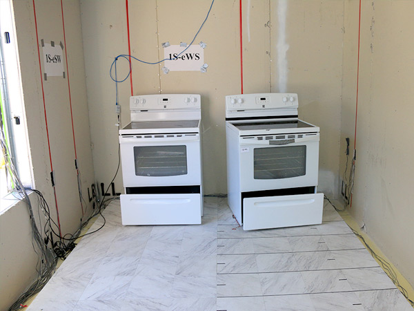 Image featuring two stoves in a room on a tile floor. One stove is flush with the wall, while the other has separated from the wall and is sitting at an angle.