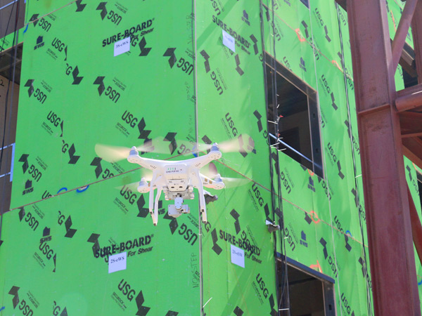 Image of a drone flying in front of a building under construction.