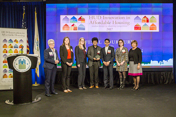  The University of Michigan at Ann Arbor team and HUD Acting Deputy Secretary Janet Golrick stand in front of the 2017 Innovation in Affordable Housing background.