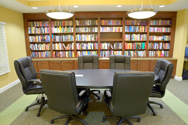 Photograph of a room with a conference table and seating in front of a wall of book-lined shelves.