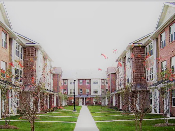 Photograph of a courtyard with three-story residential buildings on three sides.