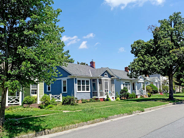 Photograph of a residential neighborhood with small, single-family detached homes and trees lining the street. 