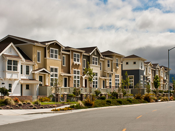 Photograph of several multi-story townhomes along a street.
