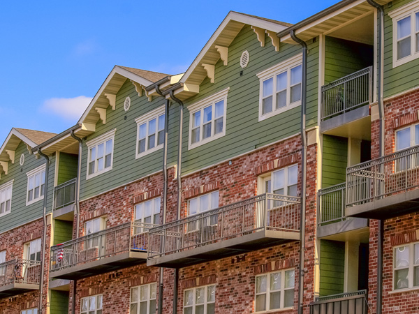 A multi-story, multifamily residential building with a façade featuring brick and siding.