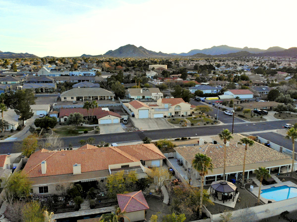 Single family homes along a grid street pattern, with a view of the mountains in the background.